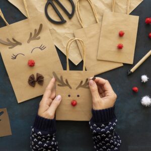 hands decorating christmas paper bags